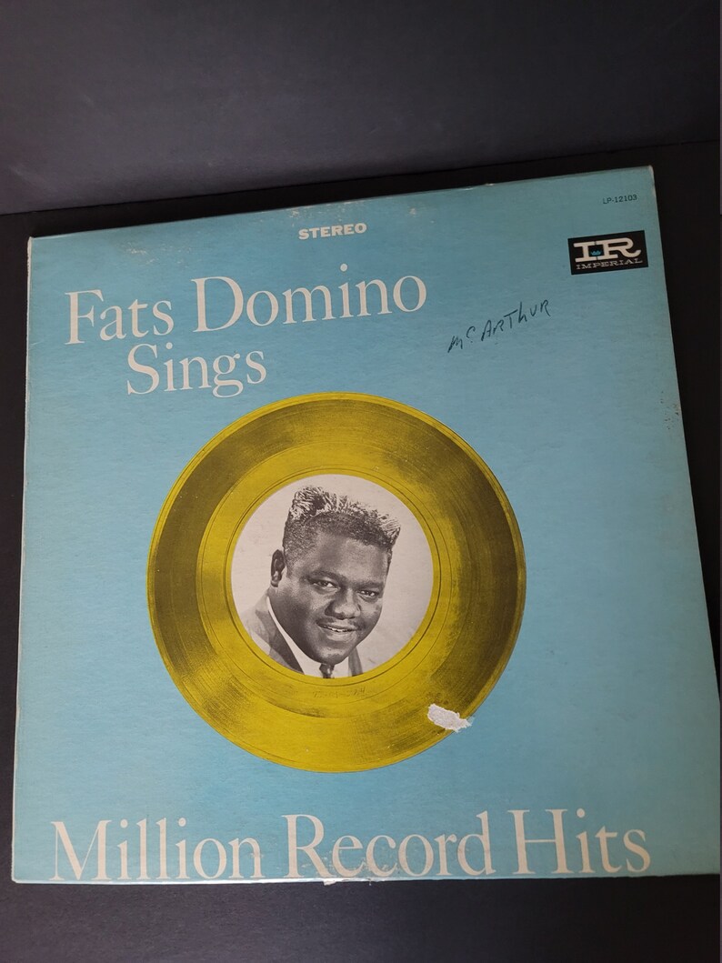 Puede incluir: Portada de &aacute;lbum de vinilo vintage para Fats Domino Sings. La portada del &aacute;lbum es azul claro con el t&iacute;tulo en blanco. Un c&iacute;rculo de color dorado presenta una foto en blanco y negro de Fats Domino. El texto "Million Record Hits" est&aacute; en la parte inferior.