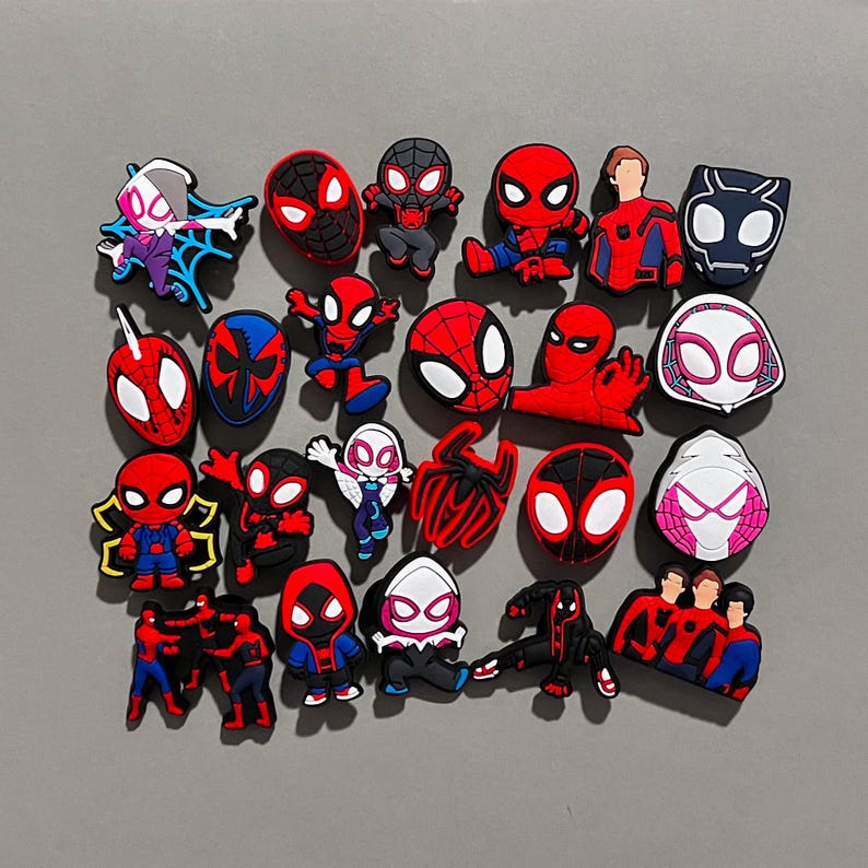 Puede incluir: Una colecci&oacute;n de 20 amuletos de zapatos de personajes de Spider-Man de dibujos animados coloridos. Los amuletos presentan diferentes versiones de Spider-Man, incluyendo Spider-Gwen, Miles Morales y el Spider-Man cl&aacute;sico rojo y azul.