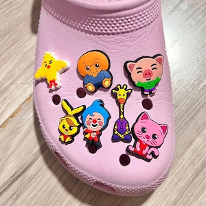 May include: A pink shoe with various colorful cartoon character shoe charms. The charms include a yellow chick, a blue elephant, a pink pig, a giraffe, a yellow bunny, a clown, and a pink cat.