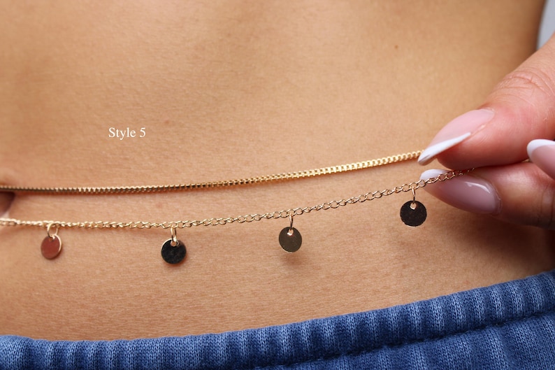 May include: A gold-toned double-strand chain necklace or waist chain featuring a smooth, solid chain and a second chain adorned with four small, circular, flat disc charms hanging at intervals. The text Style 5 is visible on the left side.