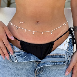 May include: A silver-toned belly chain featuring a delicate link chain with evenly spaced dangling star charms and small circular accents. The text "Style 2" is printed in white on the left side of the midsection above the chain.
