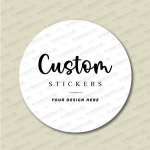 May include: A white, circular sticker featuring the text "Custom Stickers" in black script and sans-serif fonts. The phrase "Your Design Here" is below the text. The background has a repeating pattern of "W Prints Lab" text.
