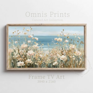 May include: A framed landscape painting featuring a coastal scene with a field of white and beige flowers in the foreground. The ocean and sky are visible in the background. The text "Omnis Prints" and "Frame TV Art" are displayed.