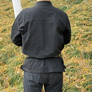 May include: A black long-sleeved shirt with a mandarin collar and a belt. The shirt is made of a soft, comfortable fabric and has a relaxed fit.