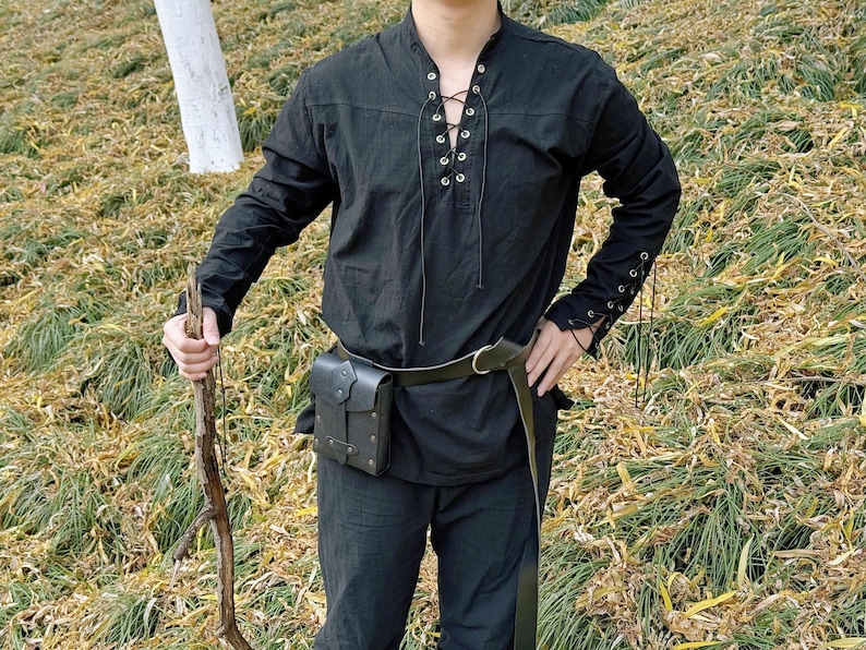 May include: A black long-sleeved shirt with a lace-up neckline and a leather belt. The shirt has a relaxed fit and is made of a soft, comfortable fabric.