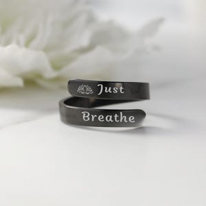 May include: A black metal ring with the words "Just Breathe" and a lotus flower engraved on it.