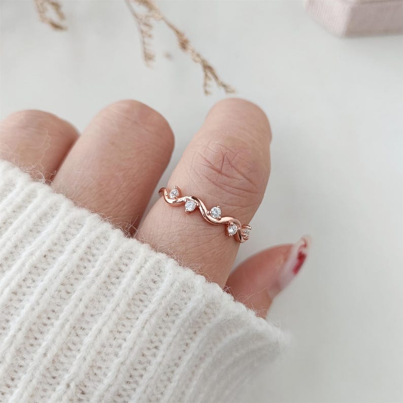 Puede incluir: Un anillo de oro rosa con una banda delicada y retorcida y peque&ntilde;as piedras transparentes.