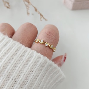 Puede incluir: Un anillo de oro con un delicado dise&ntilde;o de vid y peque&ntilde;as piedras transparentes.