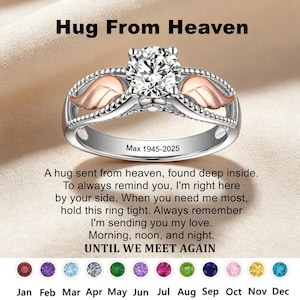 May include: A silver-toned ring featuring a central round clear stone, rose gold-colored angel wings on the sides, and the engraved text Max 1945-2025. The image includes the text Hug From Heaven and a poem ending with UNTIL WE MEET AGAIN.