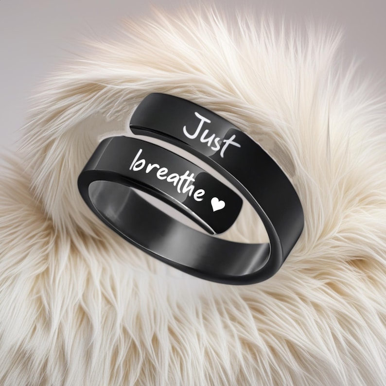 May include: Black ring with the words "Just breathe" and a small heart engraved on it.