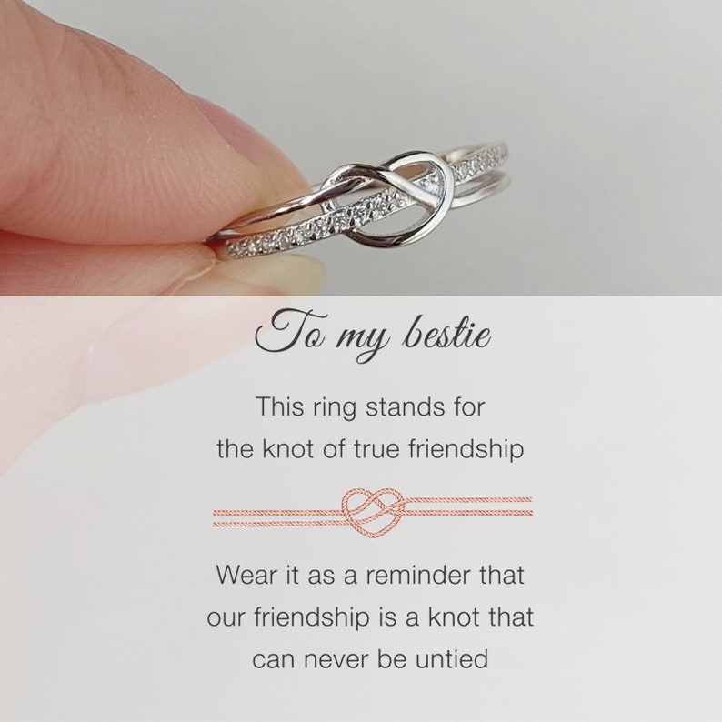 May include: A silver ring with a knot design and small clear stones. The ring is held by a hand and the text "To my bestie" is written below the ring. The text "This ring stands for the knot of true friendship" is written below the ring. The text "Wear it as a reminder that our friendship is a knot that can never be untied" is written below the ring.