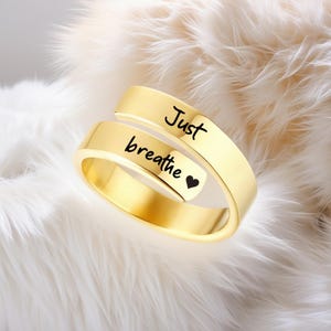 May include: Gold-toned adjustable ring with the words "Just breathe" and a small heart engraved on the band.