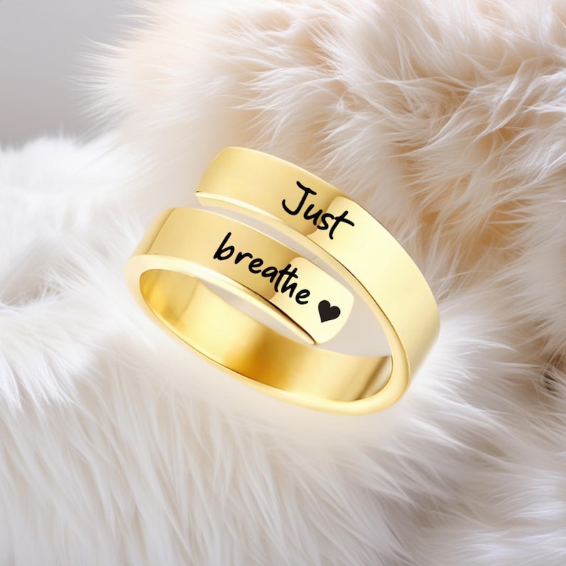 May include: Gold-toned adjustable ring with the words "Just breathe" and a small heart engraved on the band.