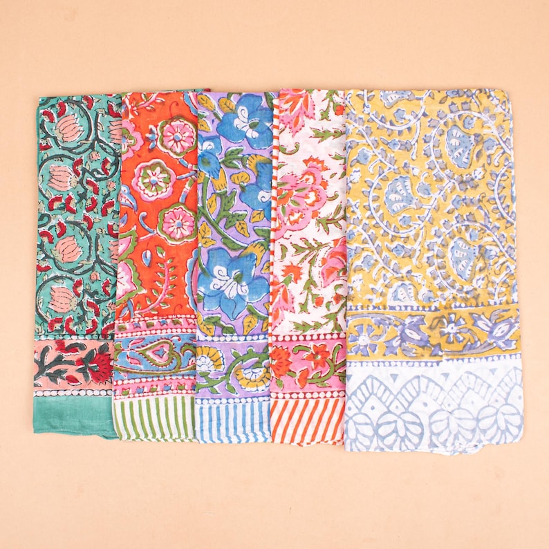 May include: A collection of colorful, floral-patterned textiles. The designs include various flowers and foliage in shades of teal, orange, purple, pink, and yellow. Each textile has a patterned border. The textiles are arranged side by side.