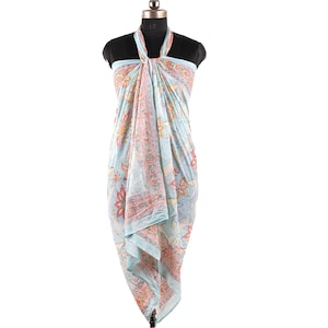 May include: A light blue sarong with a floral print. The sarong is tied around a mannequin to show how it can be worn.