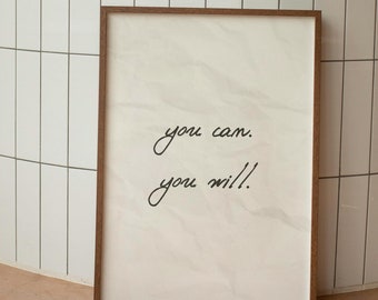 May include: A framed motivational poster with a white background and brown frame. The poster features the text "you can. you will!" written in black cursive.