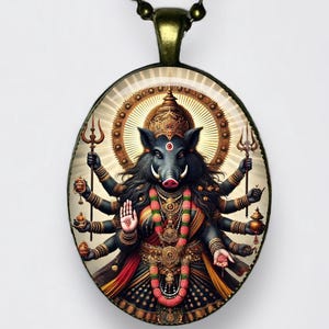 May include: Oval pendant necklace featuring a detailed illustration of a multi-armed deity with a boar-like face, adorned with ornate jewelry and holding various objects. The pendant has a bronze-colored chain.