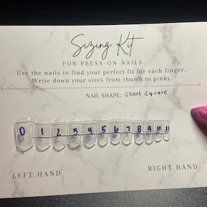 May include: Sizing kit for press-on nails with a row of 12 clear plastic nail tips numbered 0 through 11. The kit is designed to help you find the perfect fit for each finger. The text "LEFT HAND" and "RIGHT HAND" is printed below the nail tips.