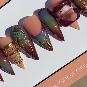 May include: A set of custom press-on nails with a variety of designs. Some nails feature a gradient of colors, gold embellishments, and a 3D lip design. The nails are displayed on a white surface with text that reads "GEMS" and "www.etsy.com/shop/gels".