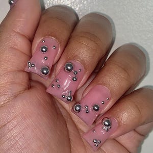 May include: Pink square-shaped press-on nails with silver 3D bubble embellishments.