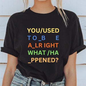 Puede incluir: Camiseta negra con el texto "YOU/USED TO_B E A_LRIGHT WHAT/HA _PPENED?" en letras de colores.