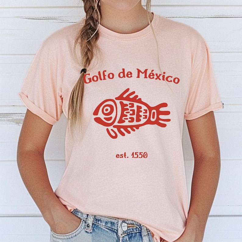 May include: A pink t-shirt with a red stylized fish and the text "Golfo de M&eacute;xico est. 1550".