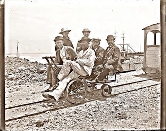 Foto en sepia: Hombres antiguos del siglo XIX apiñados en una vagoneta de ferrocarril ~ trajes y sombreros