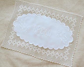 MANTELERÍA ~ Dos manteles vintage ~ uno blanco ovalado bordado con la palabra "PAN" y otro rectangular de ganchillo con borde de picot.