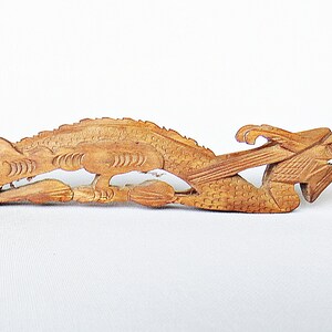 May include: A wooden carving of a dragon, with intricate details and a light brown color.