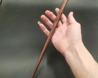 Pode incluir: Uma varinha de madeira marrom escura com um design retorcido. A varinha mede aproximadamente 30 cm de comprimento.