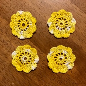 May include: Four crocheted yellow and white doilies with a circular design.