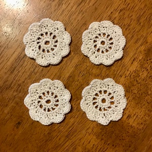 May include: Four white crocheted doilies with a floral design.