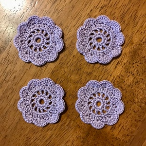 May include: Four lavender crocheted doilies with a delicate floral design.