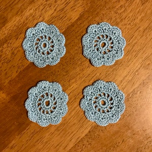 May include: Four light blue crocheted doilies with a floral design.