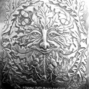 May include: A silver embossed metal plaque with a detailed design of a Green Man face surrounded by oak leaves and acorns. The plaque reads "Happy 30th Anniversary".