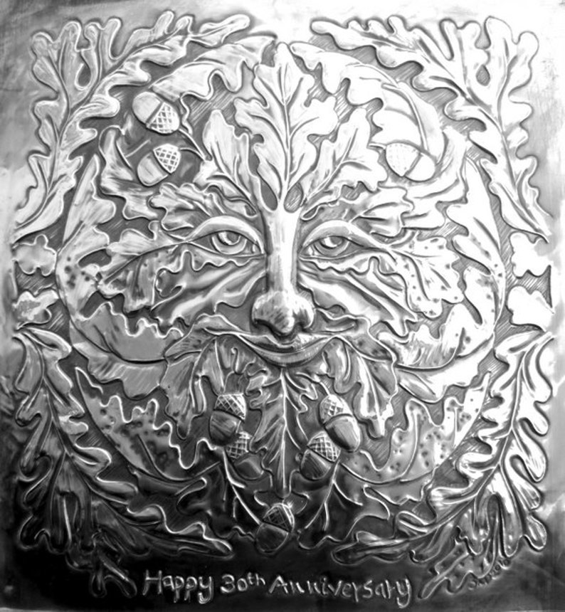 May include: A silver embossed metal plaque with a detailed design of a Green Man face surrounded by oak leaves and acorns. The plaque reads "Happy 30th Anniversary".