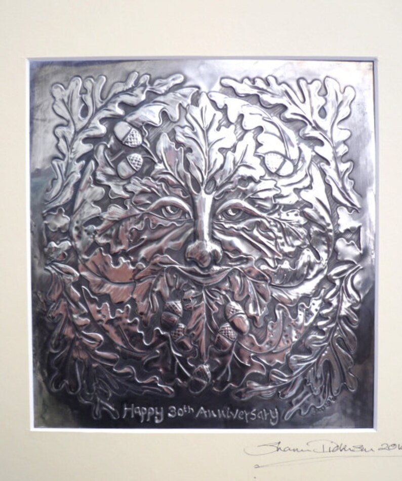 May include: A silver embossed metal plaque with a green man face surrounded by oak leaves and acorns. The plaque reads "Happy 30th Anniversary" and is signed "Jamie Liddiard 2012".