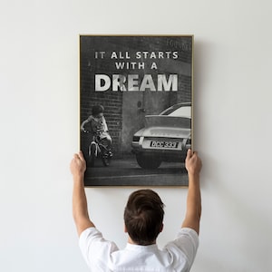 May include: Black and white photo print of a child riding a bicycle in front of a classic car with the text "It all starts with a dream" printed on the top of the image.
