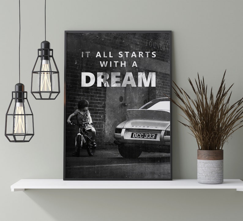 May include: Black and white photo print of a child riding a bicycle in front of a vintage car with the text "It all starts with a dream".