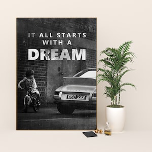 May include: Black and white photograph of a child riding a bicycle in front of a vintage Porsche with the text "It all starts with a dream" on a brick wall.