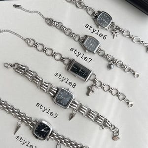 Puede incluir: Diez pulseras de cadena plateadas con diferentes dijes y esferas de reloj cuadradas negras. Las pulseras están etiquetadas como "style6", "style7", "style8", "style9" y "style10".