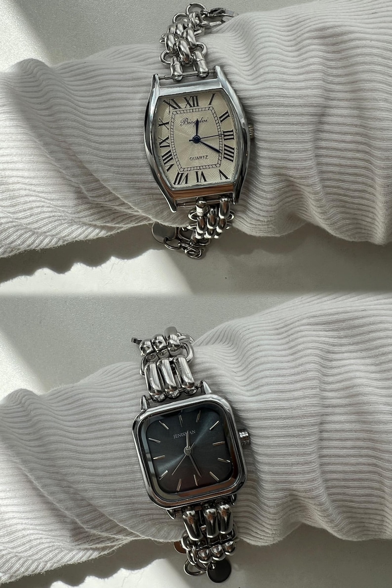 May include: Two silver watches with chain link bands. The top watch has a white face with black Roman numeral hour markers and the text "QUARTZ". The bottom watch has a black face with silver hands and the text "TEMSIAN".