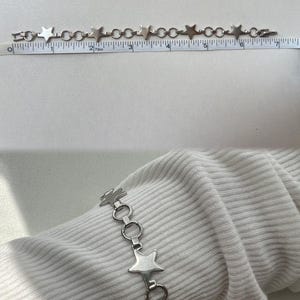 May include: A silver chain bracelet with star-shaped links. The bracelet is approximately 7 inches long.