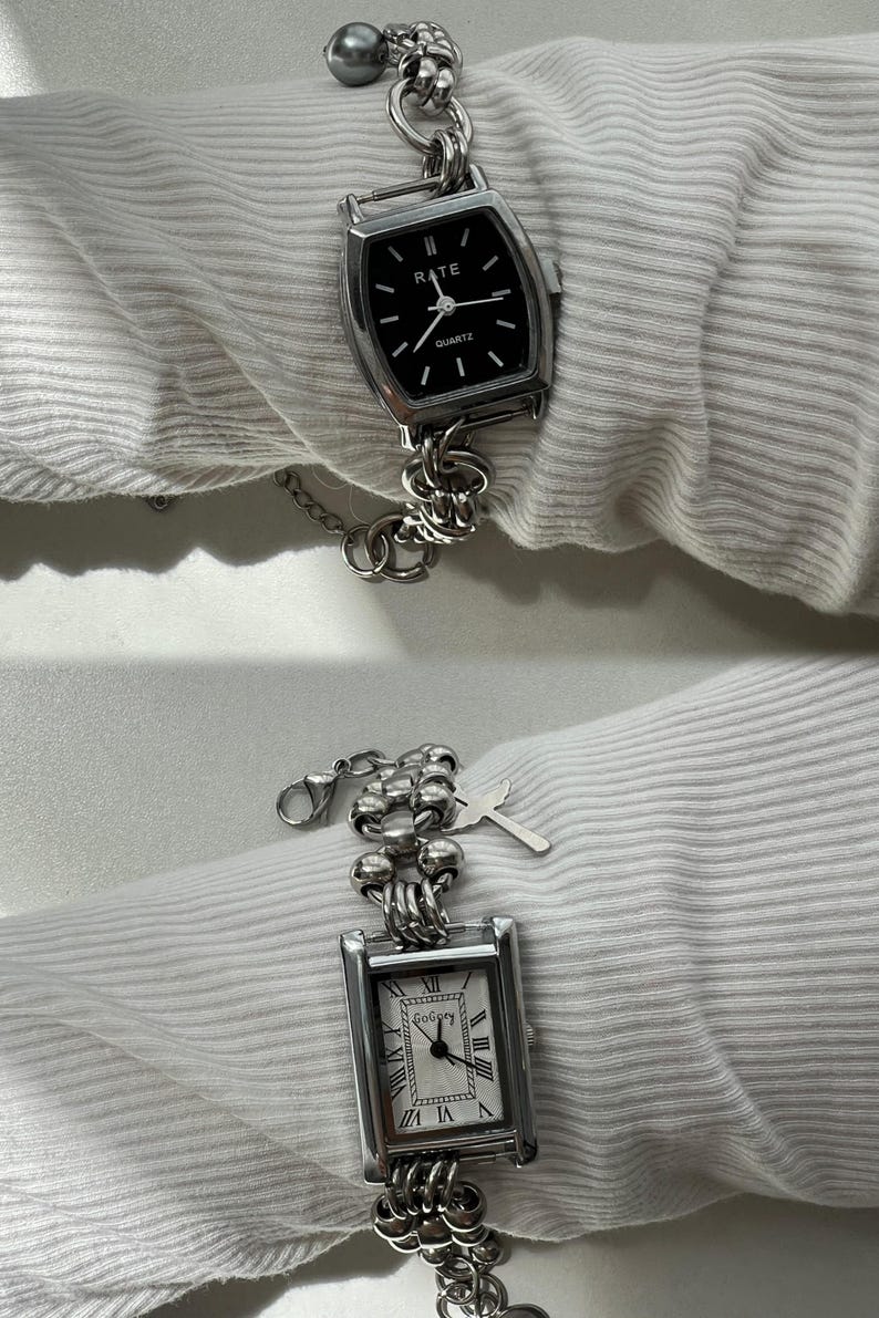 May include: Two silver watches with square faces and chain link bands. The top watch has a black face with white hands and the text "RATE QUARTZ". The bottom watch has a white face with black Roman numeral markings and black hands.