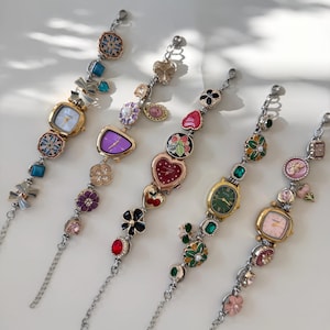 May include: Five decorative bracelet watches with various colourful embellishments. Each watch features a different face shape and colour, including square, oval, and heart-shaped designs. The bracelets are adorned with floral, gemstone, and charm accents.