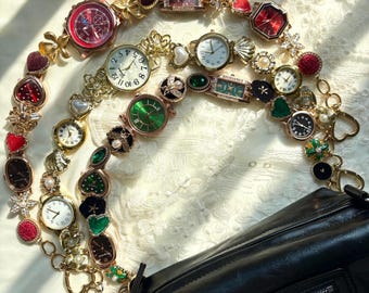 May include: A collection of decorative wristwatches with diverse coloured faces and embellishments, including red, green, and white. The watches are linked by chains and charms, draped over a black handbag.