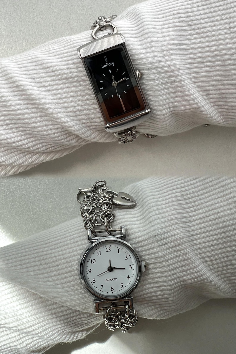 May include: Two silver wristwatches with chain link bands. The top watch has a black face with the word "GoGory" printed on it. The bottom watch has a white face with black numbers and hands and the word "QUARTZ" printed on it.