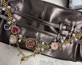 May include: A metallic bronze handbag with a decorative chain featuring multiple small watches in various shapes and colors. The chain is adorned with faux pearls and gold-toned metal. The text "Style 1" is visible.