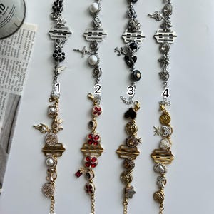 May include: Eight decorative bracelets with various charms, including flowers, crosses, and pearls. The bracelets feature silver and gold tones, with some adorned with black and red accents. Each bracelet has a unique design.