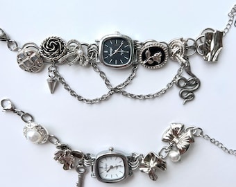 May include: Two silver charm bracelets with square analog watches. The top bracelet has a rose, a snake, a key, and a pearl charm. The bottom bracelet has a bow, a key, and a pearl charm.